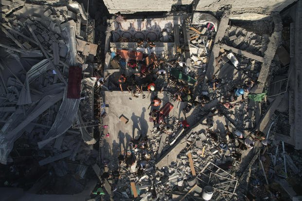 Palestinians inspect the rubble of buildings hit by an Israeli airstrike at Al Shati Refugee Camp