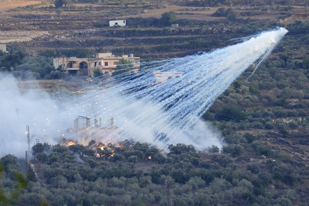 A shell from Israeli artillery explodes over a house in Lebanon