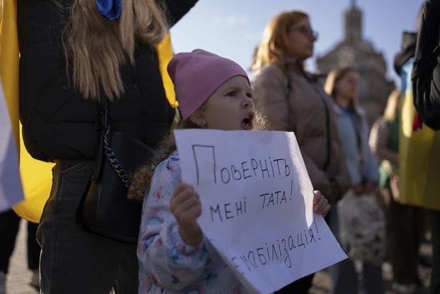 Liliia, who waits for her father to return from the frontline, holds a poster reading "Bring my father back. Demobilization!"