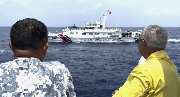 Philippine special envoy to China Teodoro Locsin Jr., right, looks at a Chinese Coast Guard ship