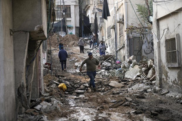 Palestinians walk through the aftermath of the Israeli military raid on Nur Shams refugee camp