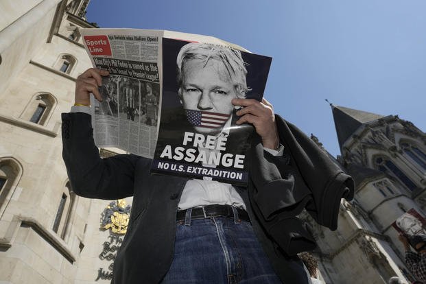 A protester reads a newspaper outside the High Court in London