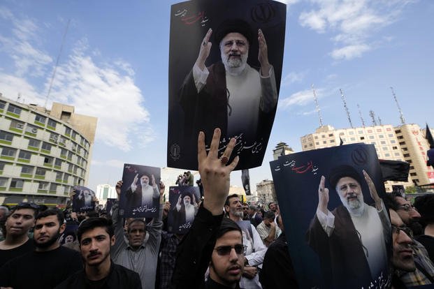 People hold up posters of Iranian President Ebrahim Raisi during a mourning ceremony