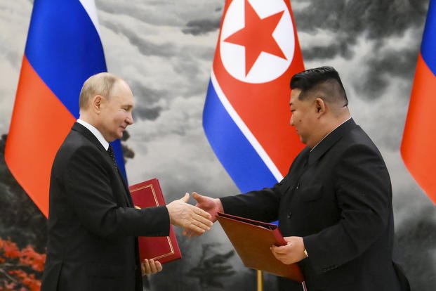 Russian President Vladimir Putin, left, and North Korea's leader Kim Jong Un exchange documents