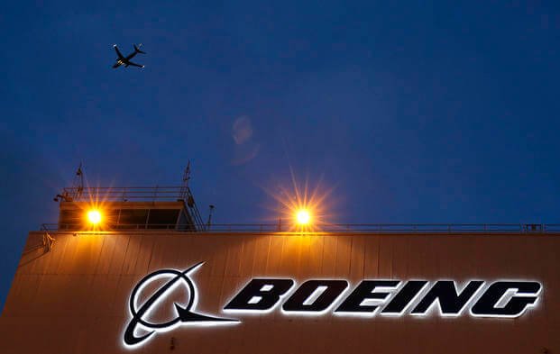 An airplane flies over a sign on Boeing's newly expanded 737 delivery center