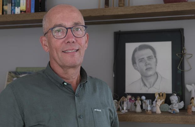 Thomas Schansman poses in front of a drawing of his son, Quinn, at his home