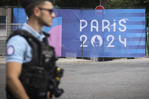 A police officer walks past a Paris Olympics canvas 