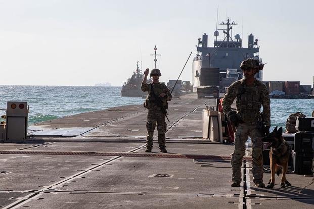 A U.S. Army soldier directs traffic across the Trident Pier