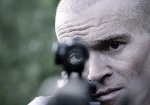 former U.S. Green Beret Jordan Goudreau holds an assault rifle in a documentary film