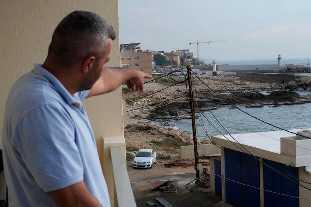 A Lebanese man points to the beach in Batroun, Lebanon.