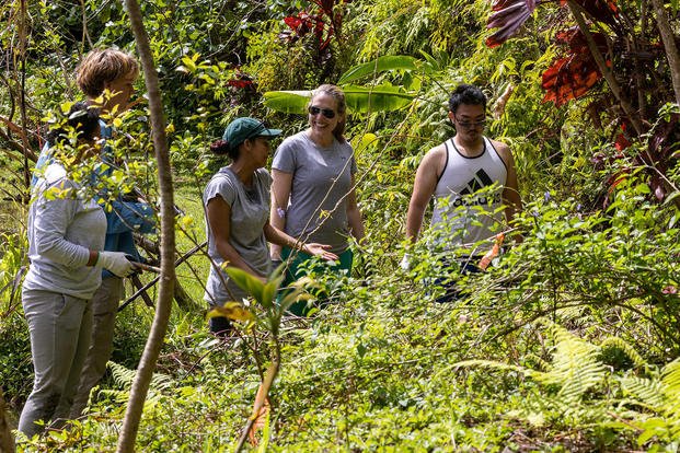 Meredith Berger, assistant secretary of the Navy for energy, installations and environment and chief sustainability officer, speaks with members of the community while removing invasive plant species at the at the Kanehekili Heiau in Hawaii.