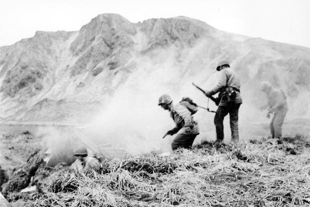 A U.S. squad armed with guns and hand grenades closes in on Japanese holdouts entrenched in dugouts during World War II