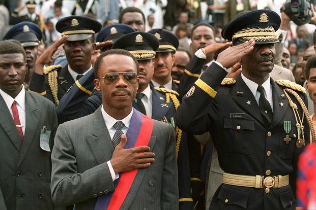 Then-Haitian President-elect Jean-Bertrand Aristide, left -- flanked by Haitian Armed forces Commander General Herard Abraham -- listens to the national anthem on Feb. 7, 1991, at the presidential palace in Port-au-Prince. 