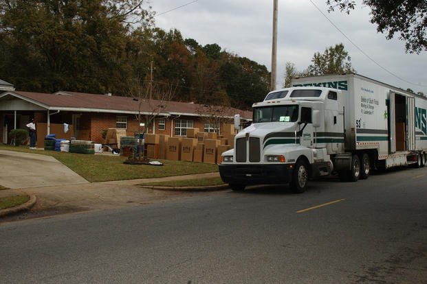 A moving truck is unloaded as a family moves into their new home. 