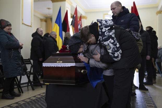 Mother and brother cry at the coffin of Ukrainian soldier.