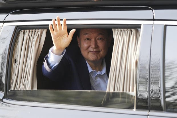 Former South Korean President Yoon Suk Yeol waves upon his arrival at the private residence
