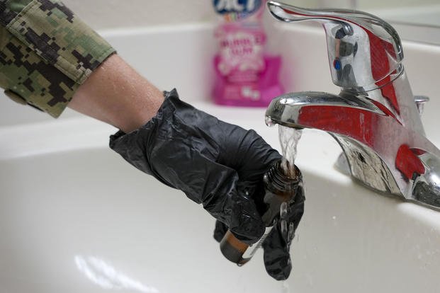 A sailor assigned to the Navy’s Water Quality Action Team (WQAT) collects a rapid-response drinking water sample at a Moanalua Terrace neighborhood residence in Honolulu.