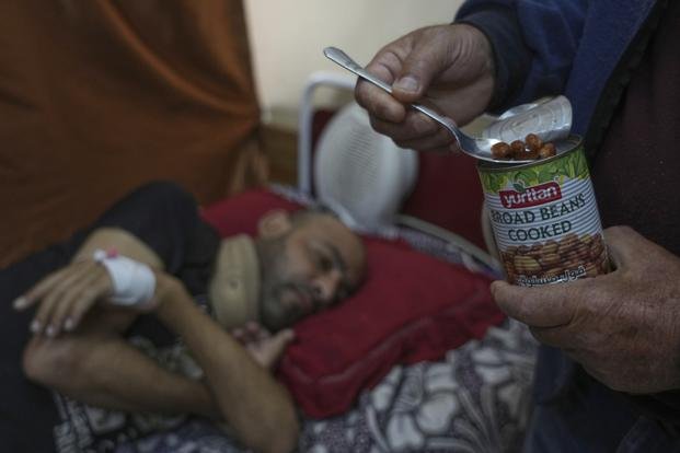 A man who was injured in a bombing and lost his foot, is fed beans by his father. 