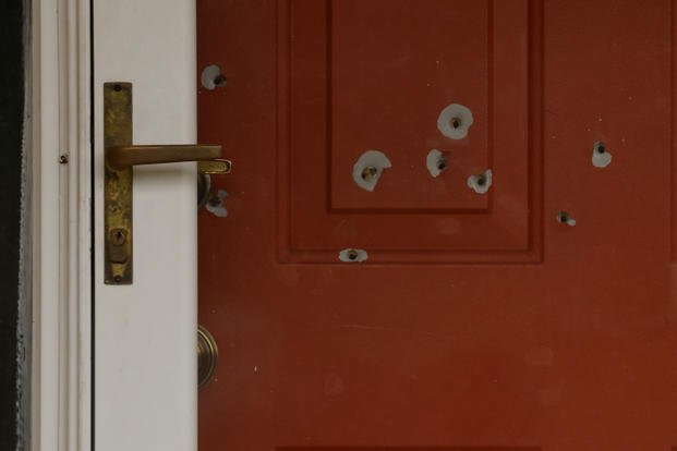 Bullet holes mark the front door of a house.