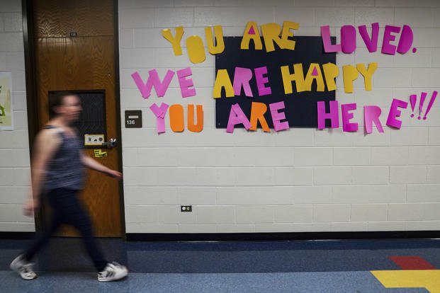A staff member walks past a message to students that hangs on the wall at Place Bridge Academy