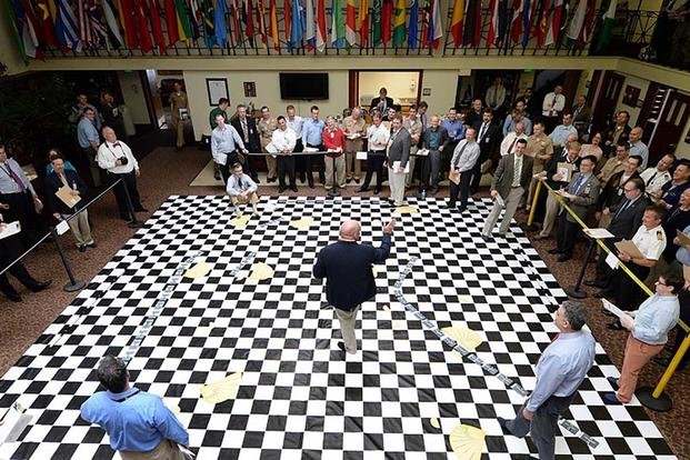 U.S. Naval War College (NWC) staff members listen to a brief during a war-game reenactment of the Battle of Jutland at NWC in Newport, Rhode Island. 