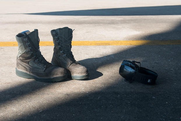 Airman's boots and hearing-protective earphones lie on the ground