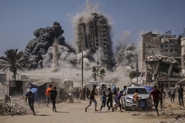 Palestinians run for cover during an Israeli airstrike on a high-rise building in Gaza City