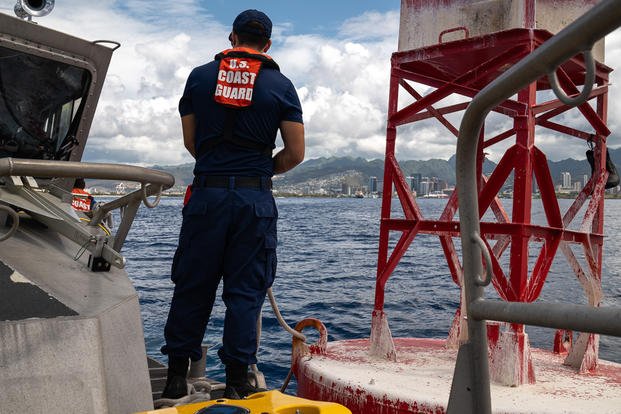 A Coast Guardsman stands on the forward deck of a 45-foot response boat-medium and prepares to handle line on a channel marker buoy outside of the Honolulu harbor entrance.