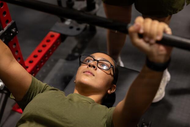A Marine performs a bench press.