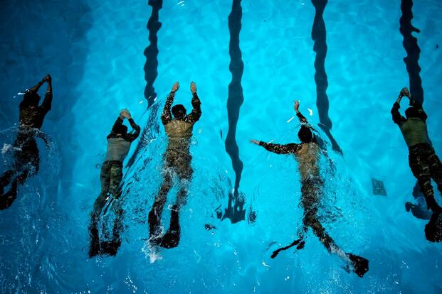 Airmen in full uniforms pictured from above swimming.