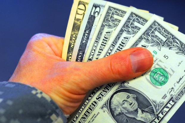 Soldier holds a stack of cash. (Photo Credit: C. Todd Lopez/U.S. Army)