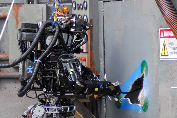 Ian, an Atlas robot with IHMC Robotics, cut a hole in a wall in a DARPA robotics competition. (DoD photo)