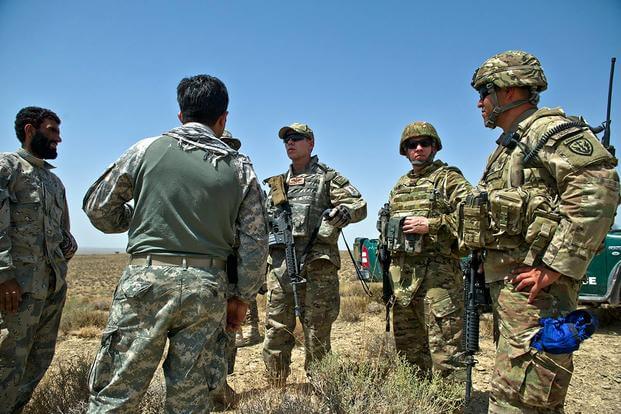 U.S. Air Force Capt. Matthew Zahler and Maj. Jason Helton, air mobility liaison officers, uses a translator to talk to Afghanistan border police. (U.S. Air Force/Master Sgt. Jeffrey Allen)