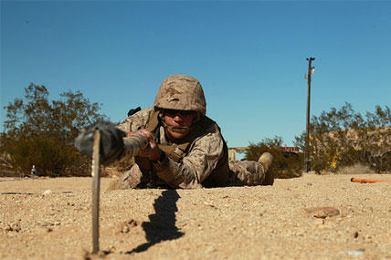 A seaman employs a bamboo sickle to search for buried IEDs at the Combat Center’s Range 800.