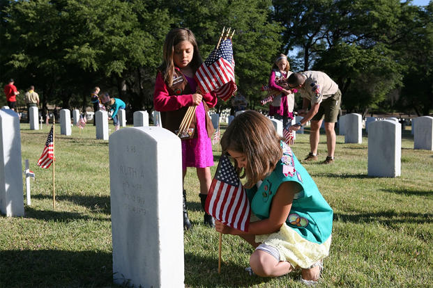 Abrihana Settles, 7, and her sister Sheaten Settles, 9, place flags on graves at the Fort Huachuca Cemetery on Monday morning before the Memorial Day ceremony. Both children are from Girl Scout Troop 9095. (Photo: Natalie Lakosil)