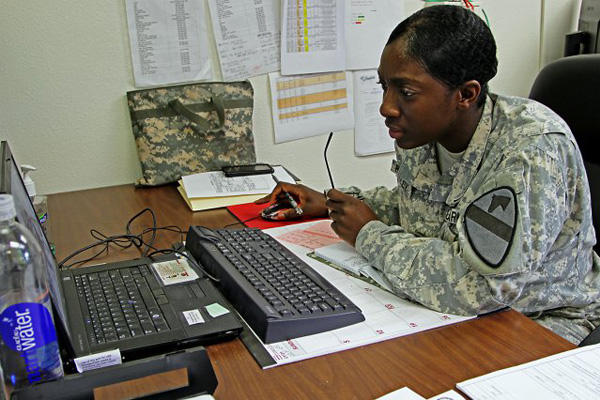 Service member using a computer at a desk.