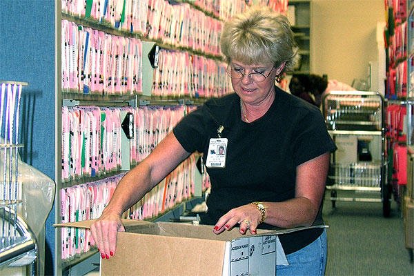 Navy Civilian Medical Records Technician Jeanette Welch boxes up medical records for safekeeping. (U.S. Navy/Rod Duren)