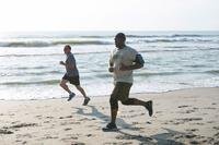 Airmen run on beach.