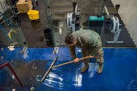 An airman at Joint Base Elemendorf-Richardson sweeps water at the base's Buckner Fitness Center a day after a 7.0 earthquake rattled the region. (U.S. Air Force)