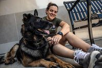 Lance Cpl. Danielle Gauthier, a Marine Corps Air Station Miramar Single Marine Program (SMP) volunteer, sits with Harold, a German shepherd up for adoption during an adoption event at San Diego. (U.S. Marine Corps/Jake McClung)