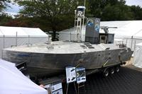 A Common Unmanned Surface Vehicle (CUSV) equipped with a box-style launcher holding two Hellfire Missiles and a .50 caliber machine gun to make a mine-hunting mission package. Textron Systems displayed the proof-of-concept, surface-warfare mission package Modern Day Marine 2019. (Matthew Cox/Military.com)