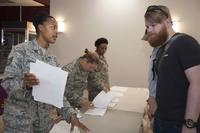 Tech. Sgt. Candace Gonzalez hands out surveys to an Individual Ready Reservist during a muster on Joint Base Andrews, Maryland, Aug. 19, 2017