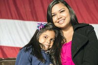 mother and daughter in front of flag