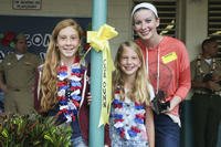 three children stand with yellow ribbon