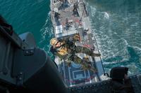 An explosive ordnance disposal technician is hoisted from a Mark VI patrol boat.