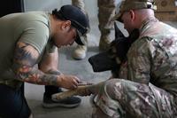 A military working dog handler draws blood  from Bubo, a patrol explosive detector dog.