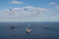 Two U.S. Air Force B-l B Lancers along with U.S. Navy F/A-18 Hornet jets fly overhead.