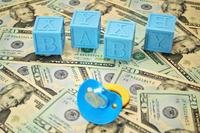 Baby bottle and blocks sitting on bed of cash