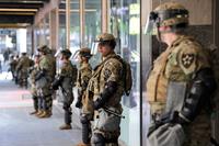 Unarmed Washington National Guard soldiers stand guard outside a closed store in Seattle.