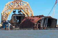 A towering crane pulls the engine room section away from the remains of the capsized cargo ship Golden Ray.